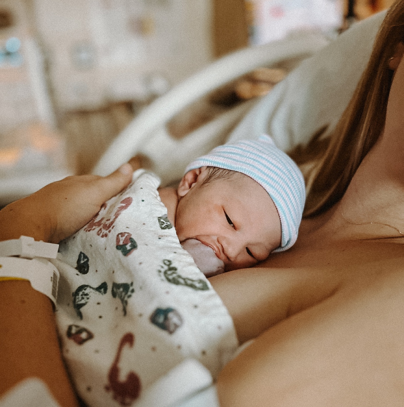 Newborn with striped hat resting peacefully on mother's chest
