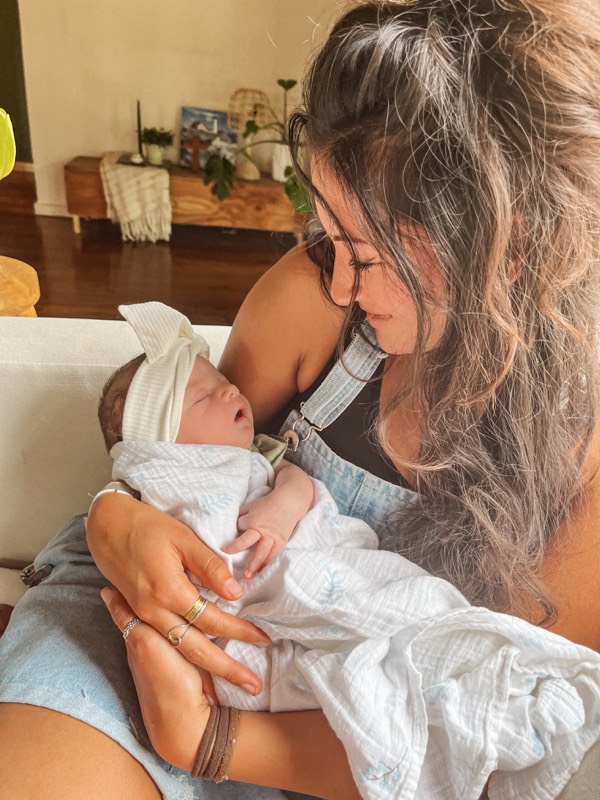 Juliana looking down tenderly at a swaddled newborn